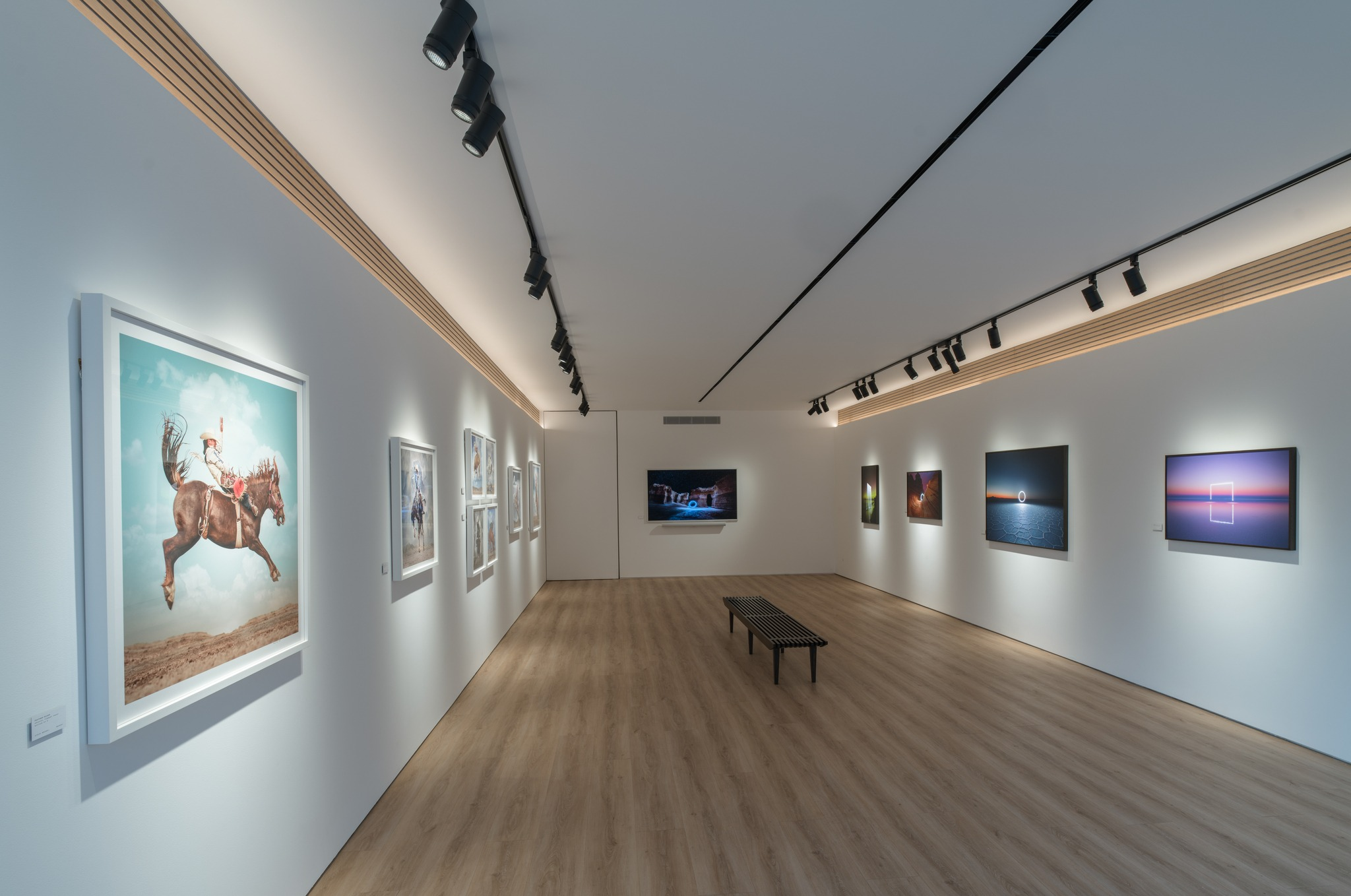 Gallery interior with black track spotlights lighting artworks on white walls